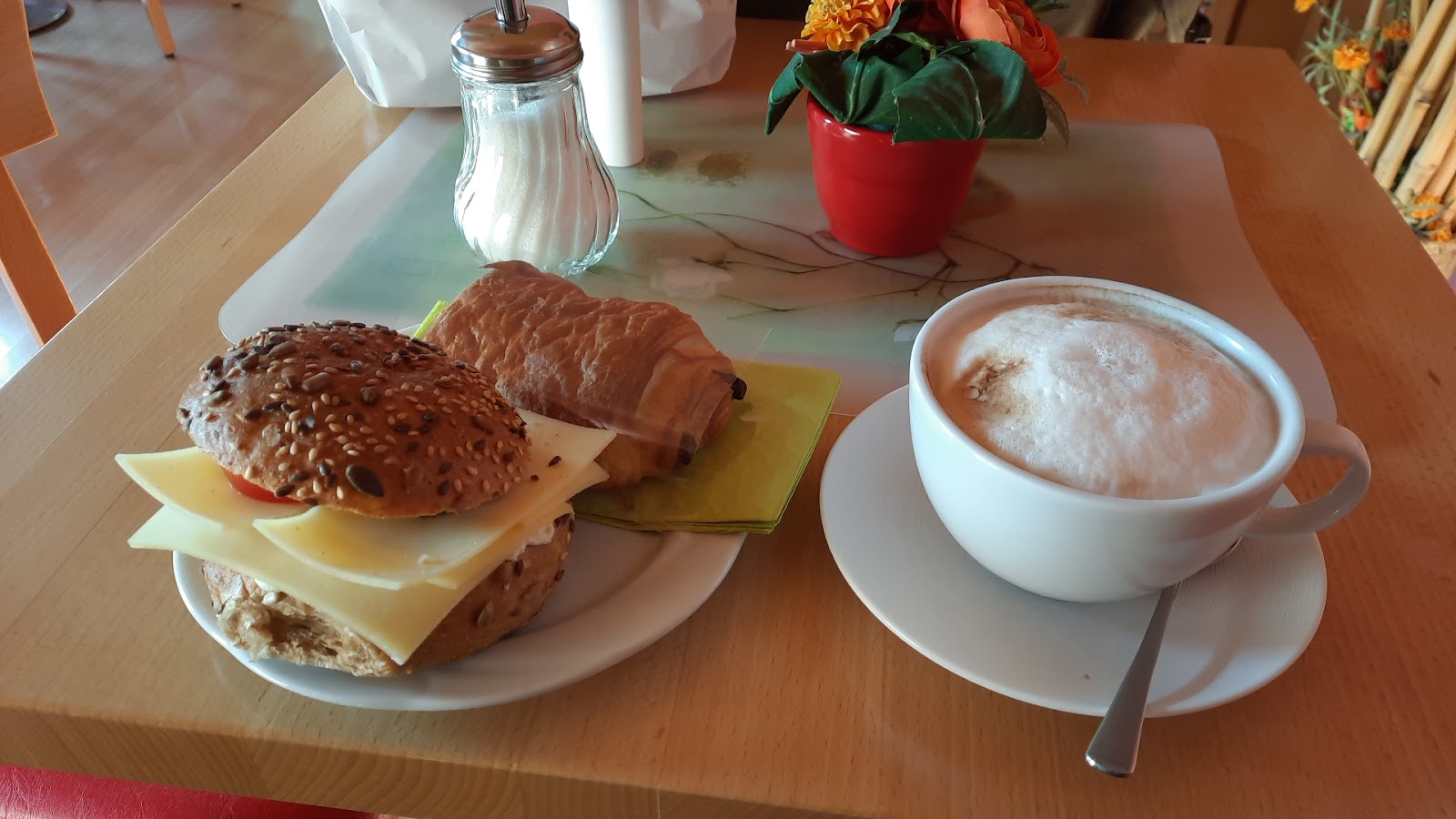 Belegtes Körnerbrötchen und Cappuccino auf dem Tisch